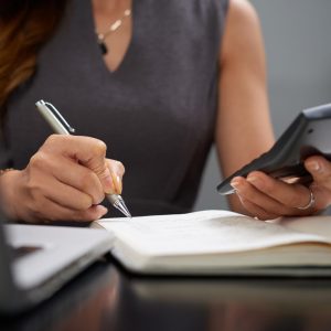 Close-up image of business lady making calculations and taking notes